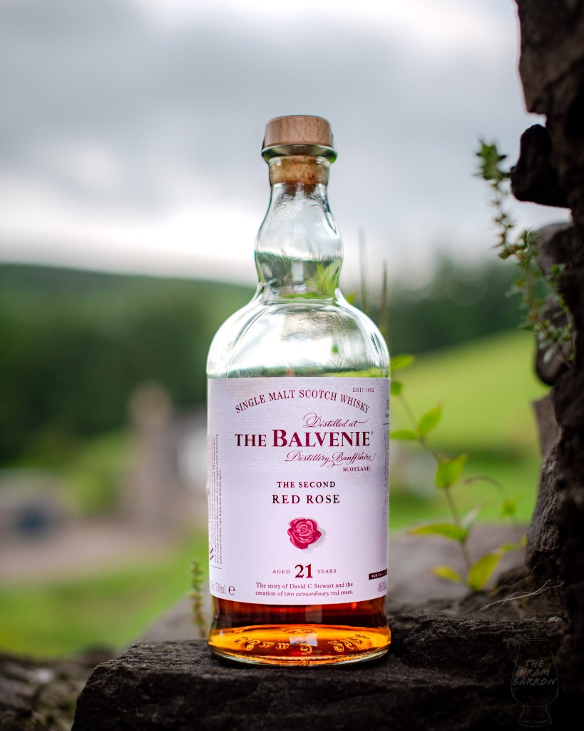 Picture of The Balvenie 21 Year Old The Second Red Rose Whisky on a wall with green fields in the background